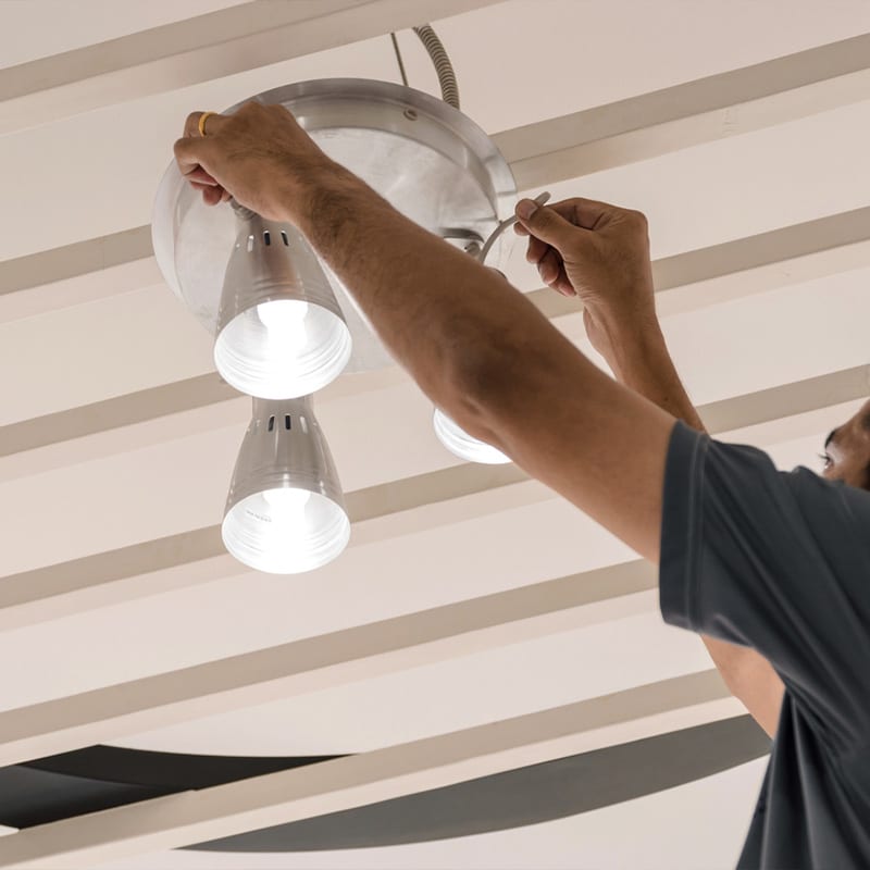 Person installing a modern ceiling light fixture, focusing on energy-efficient lighting solutions.
