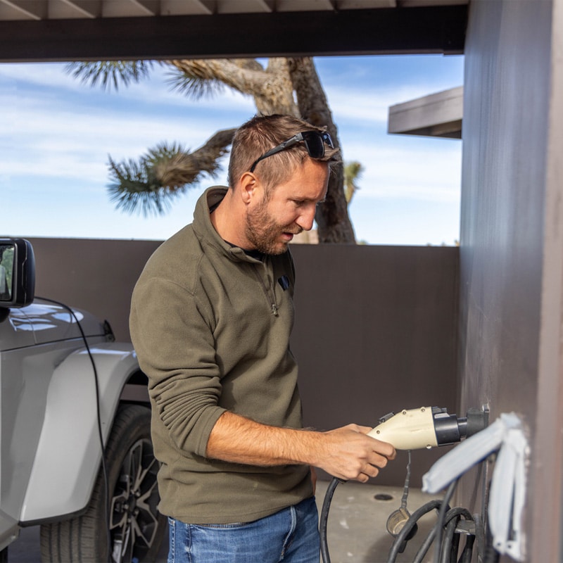 Man using an electric drill outside near an SUV.