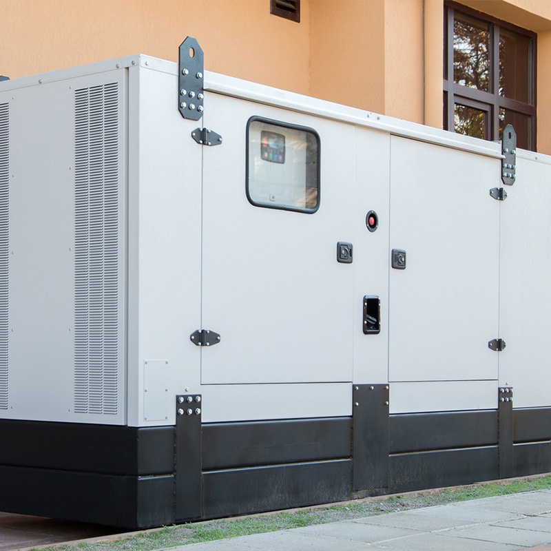 Outdoor industrial generator near a building, providing backup power.