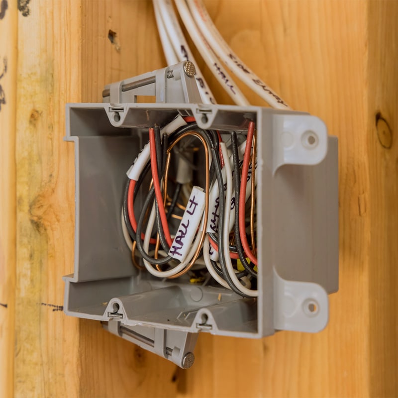 Electrical junction box with labeled wires in a wooden wall, showing organized home wiring connections.