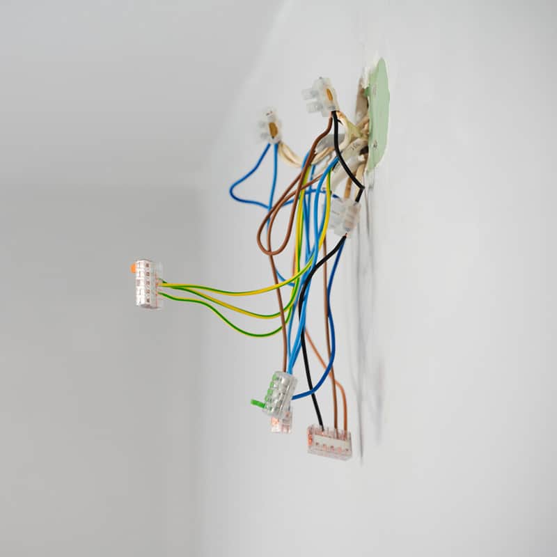 Exposed electrical wires protruding from wall, illustrating home electrical installation or repair project.