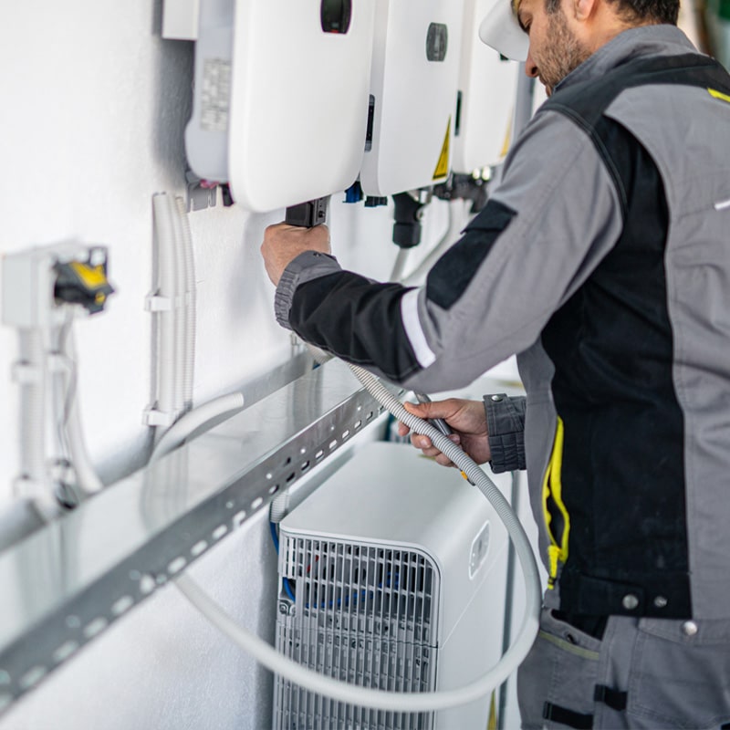 Technician installing and setting up solar power system inverter in a modern energy facility.