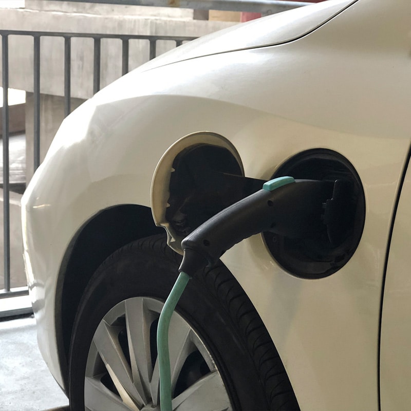 Electric car charging with plug in a parking lot, highlighting eco-friendly transportation options.