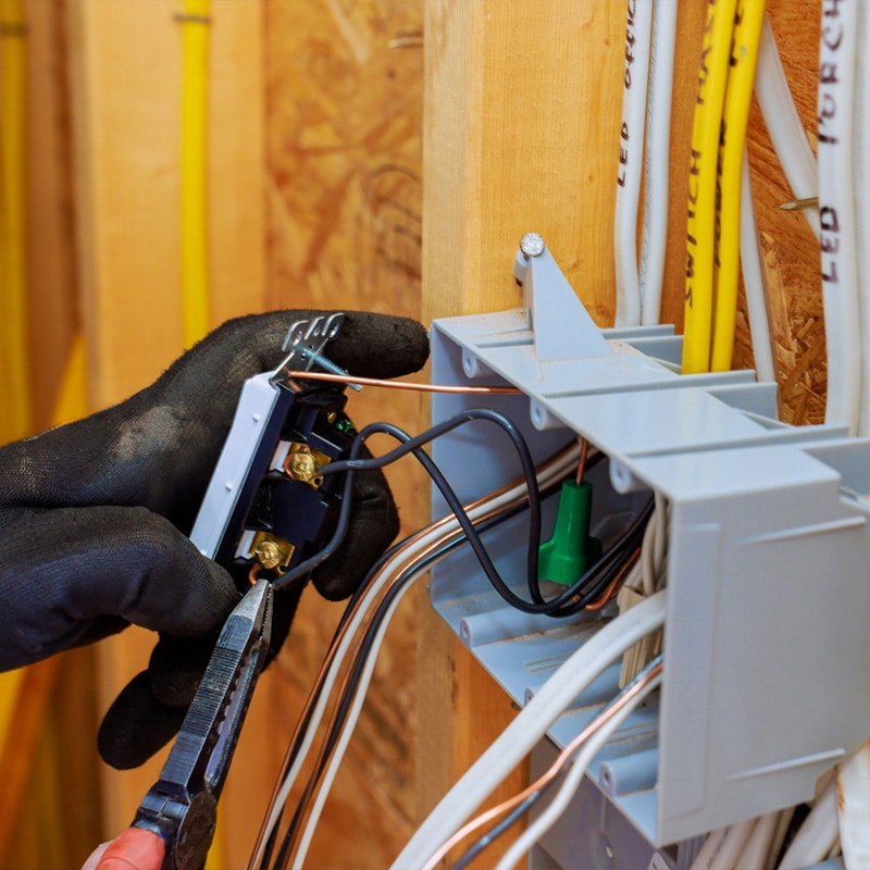 Electrician installing wiring and switches in a junction box during a home renovation.